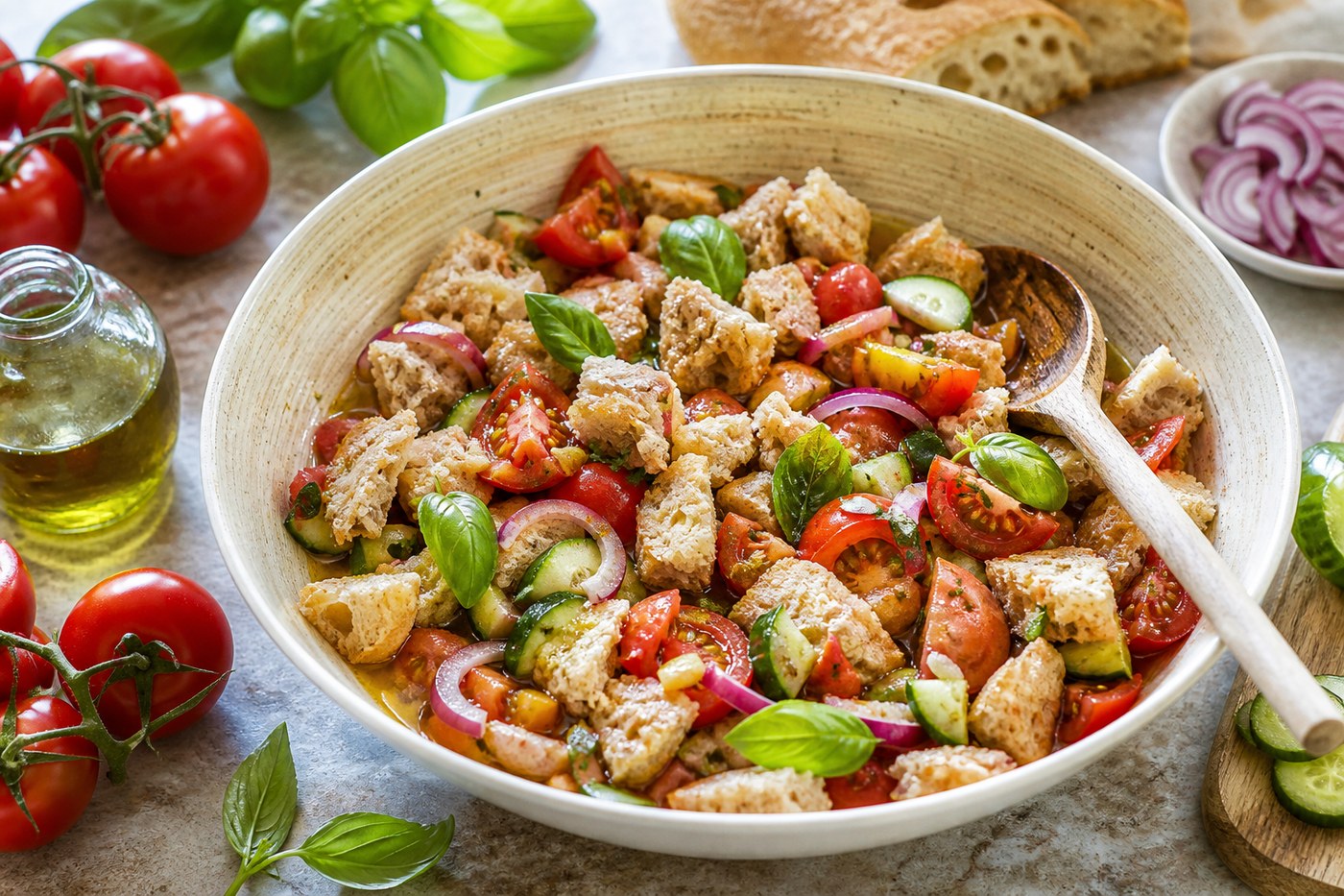 Míchání panzanelly v míse s chlebem, rajčaty, okurkou, cibulí a bazalkou